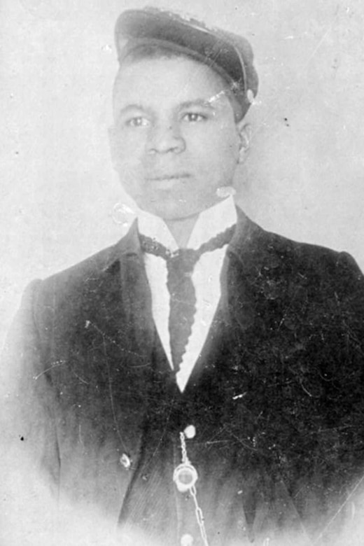 A black and white photo of a man in a suit and hat posing for a portrait.