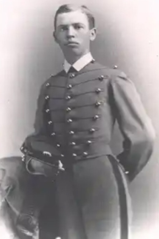 A black and white photo of a man in a dress military uniform posing for a photo.