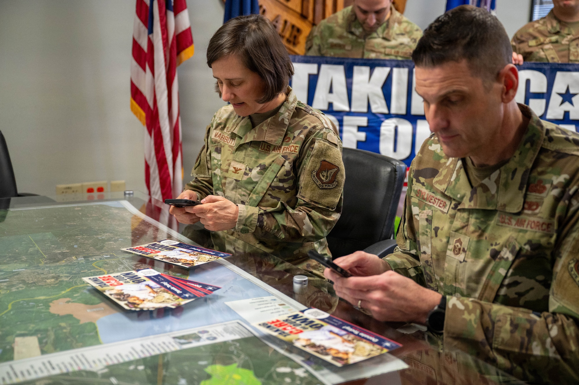 U.S. Air Force Col. Lisa Mabbutt, 673d Air Base Wing and Joint Base Elmendorf-Richardson commander, and Chief Master Sgt. Michael Sylvester, 673d ABW command chief, navigate the online page for the Air Force Assistance Fund on their cell phones at JBER, Alaska, April 6, 2026.