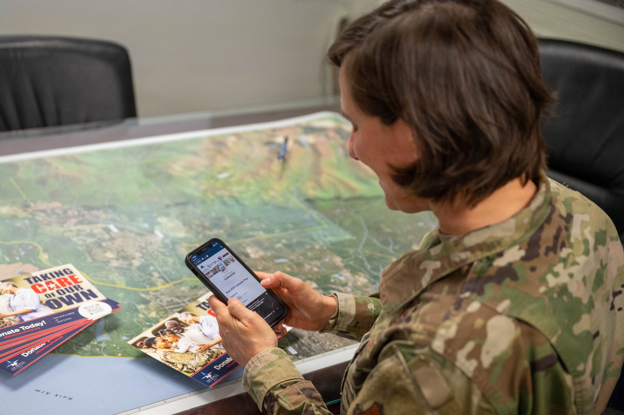 U.S. Air Force Col. Lisa Mabbutt, 673d Air Base Wing and Joint Base Elmendorf-Richardson commander, and Chief Master Sgt. Michael Sylvester, 673d ABW command chief, navigate the online page for the Air Force Assistance Fund on their cell phones at JBER, Alaska, April 6, 2026.