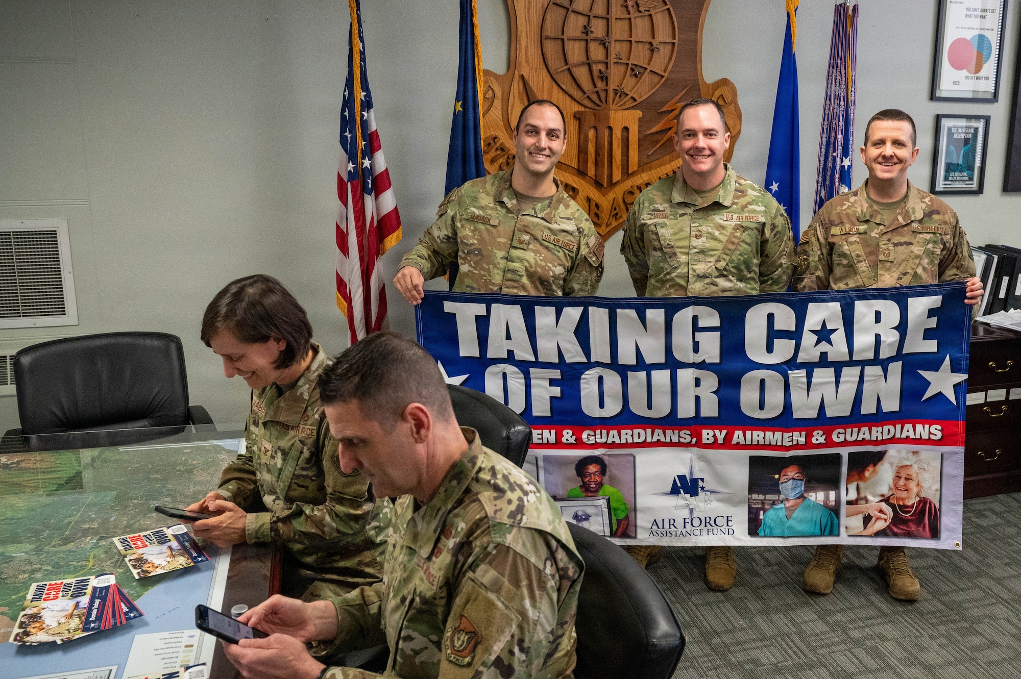 U.S. Air Force Col. Lisa Mabbutt, 673d Air Base Wing and Joint Base Elmendorf-Richardson commander, and Chief Master Sgt. Michael Sylvester, 673d ABW command chief, navigate the online page for the Air Force Assistance Fund on their cell phones at JBER, Alaska, April 6, 2026.