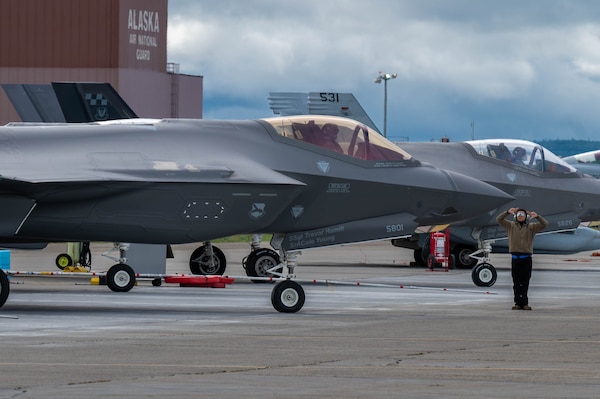 A U.S. Air Force Airman assigned to the 95th Fighter Generation Squadron marshals a F-35A Lightning II during Red Flag-Alaska 25-3 at Eielson Air Force Base, Alaska, July 25, 2025. In addition to aircrew, RF-A provides training for deployed maintenance and support personnel to sustain large-force deployed air operations. (U.S. Air Force photo by Senior Airman Alexzandra Gracey)