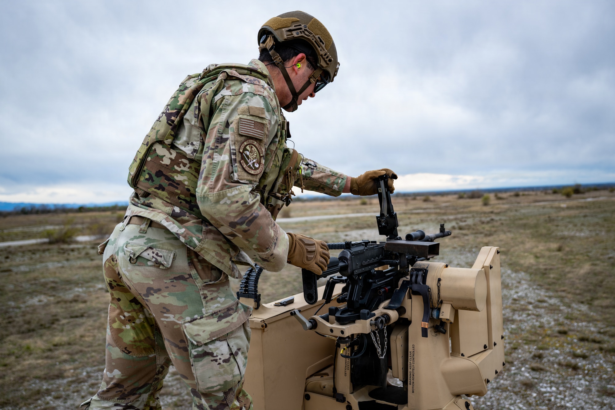 An airman attaches a M240B to a CROWS system.