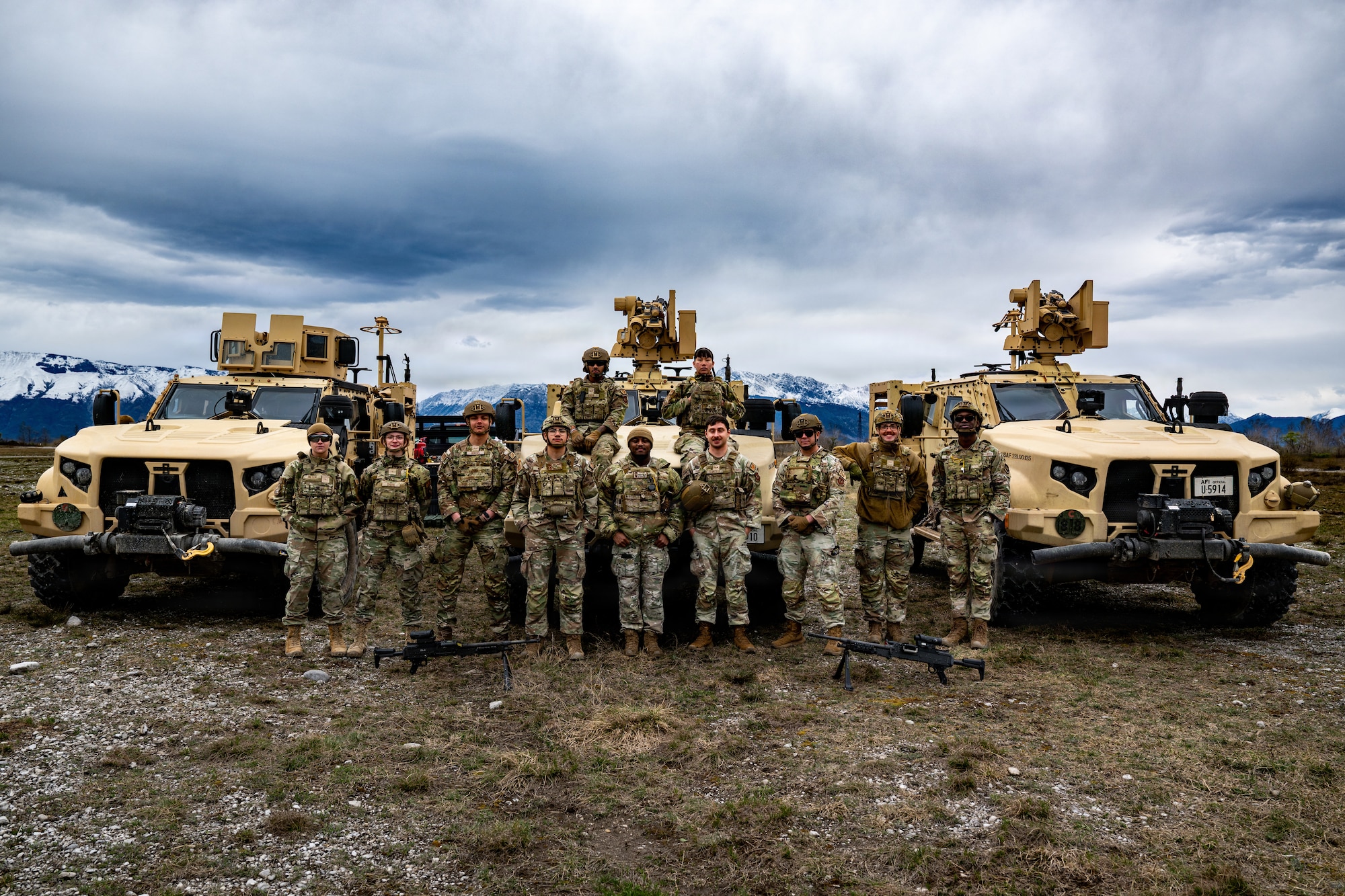 A group of airmen stand in front of three Joint Light Tactical Vehicles.