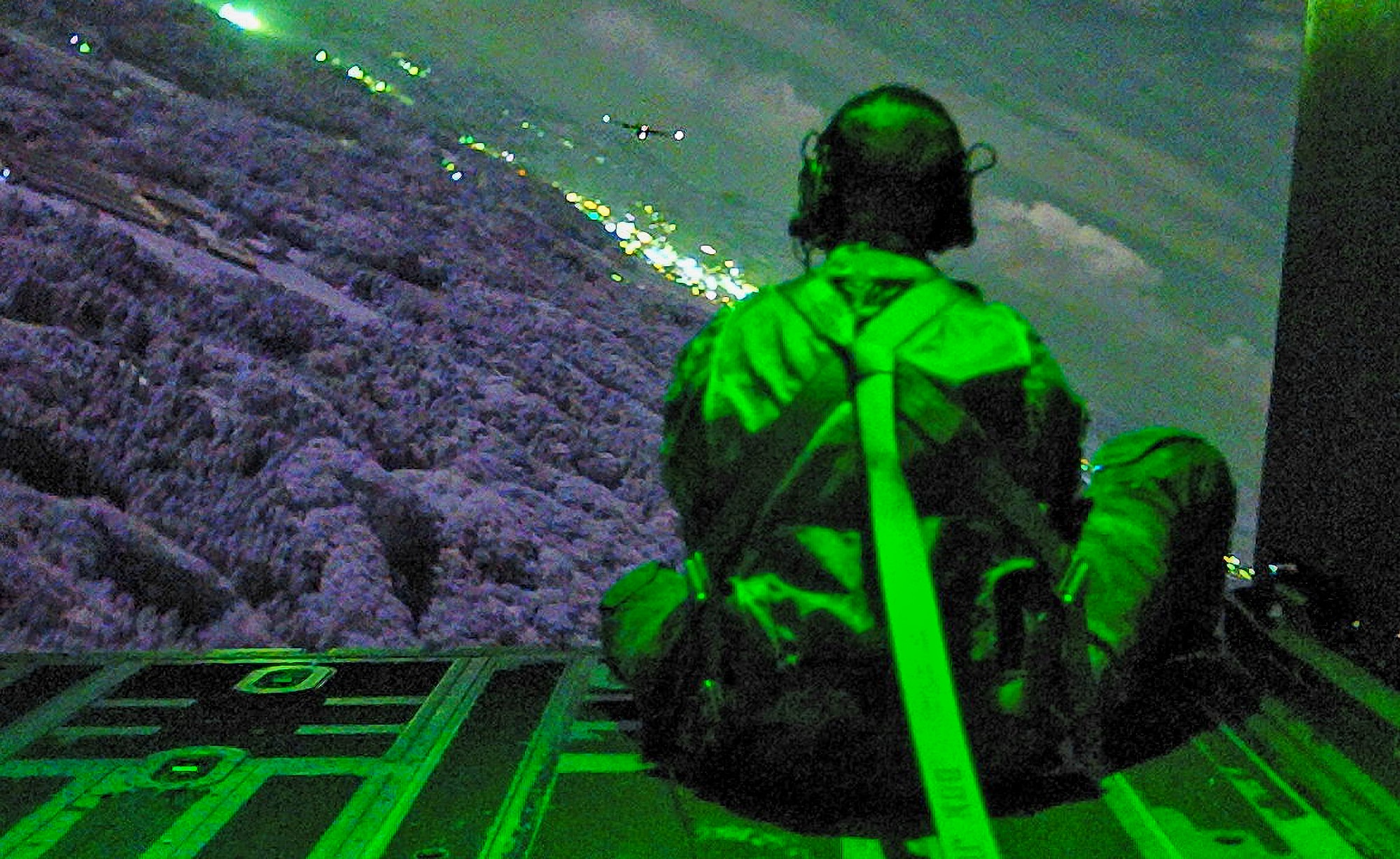 A U.S. Air Force loadmaster assigned to the 353rd Special Operations Wing sits on the ramp of an MC-130J Commando II during low level maneuvers over Fukuoka, Japan.