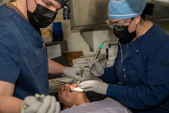 U.S. Navy Lt. Shane Burns, left, and Hospital Corpsman 3rd Class Jaina Shappee perform a wisdom tooth removal on a patient aboard Nimitz-class aircraft carrier USS Dwight D. Eisenhower (CVN 69), Feb. 25, 2026. Eisenhower is moored at Norfolk Naval Shipyard for a Planned Incremental Availability maintenance period. (U.S. Navy photo by Mass Communication Specialist Seaman Melina Rossi)