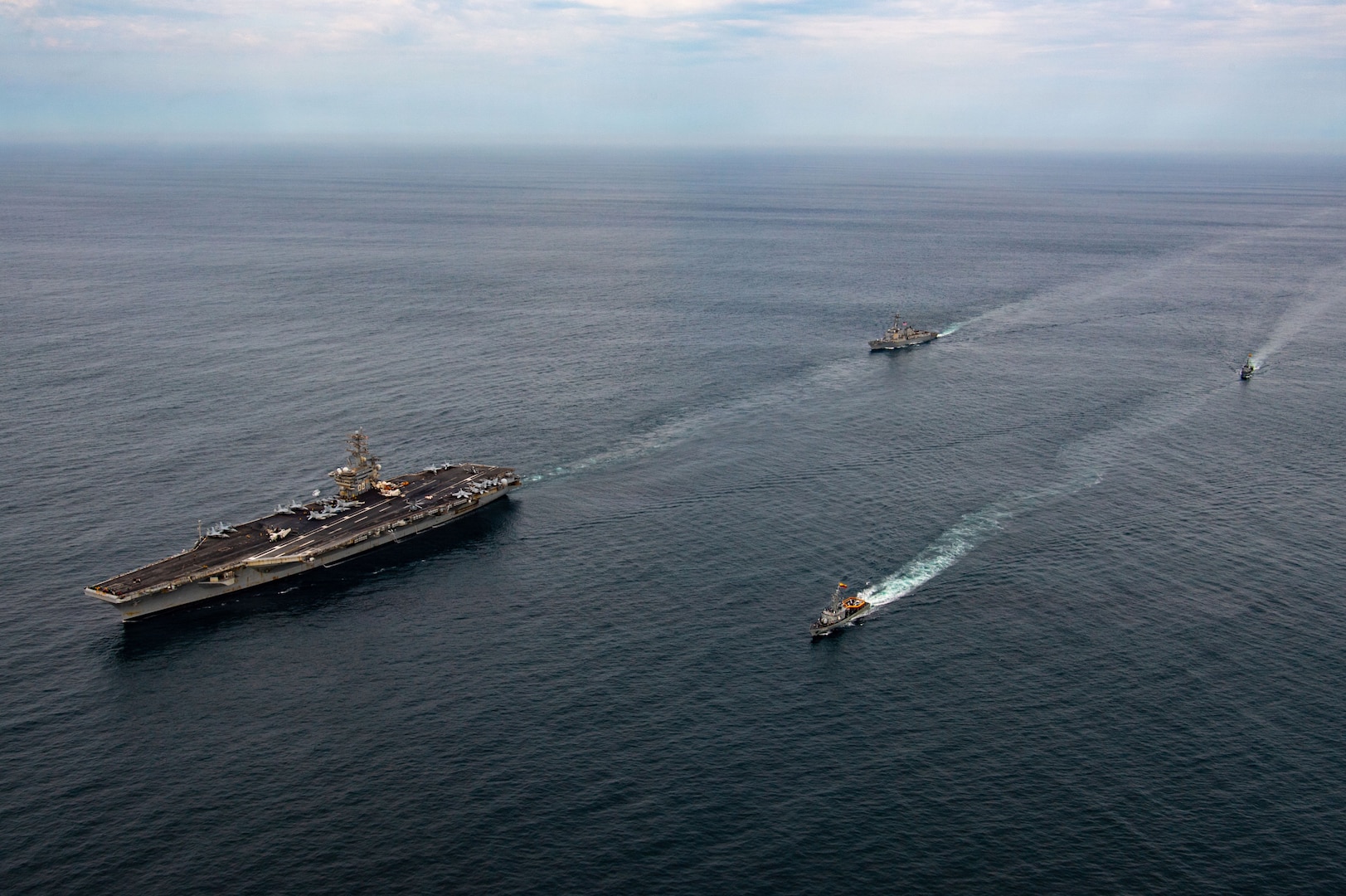 Overhead view of naval warships sailing in formation in the open sea.