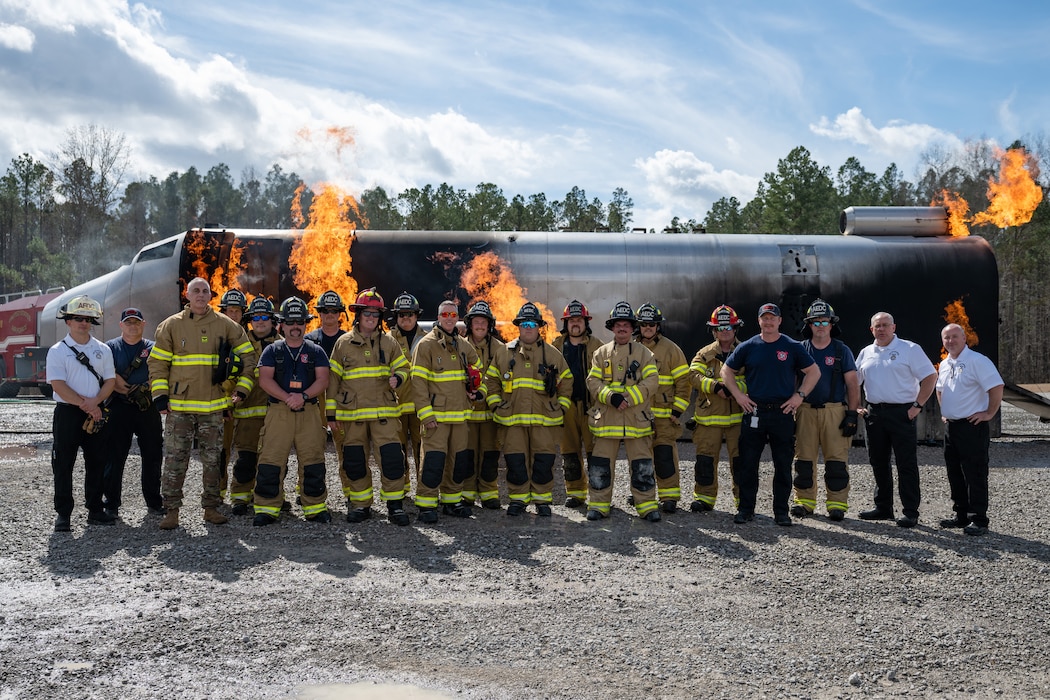 Arnold Engineering Development Complex leadership and some of the Arnold Air Force Base Fire and Emergency Services firefighters who participated in the recent live fire training conducted by Arnold FES pose for a photo in front of an aircraft fuselage fire simulator March 6, 2026, at Arnold AFB, Tenn. Arnold AFB is the headquarters of AEDC. The annual training is conducted by FES to maintain readiness in the event of an emergency and to meet National Fire Protection Association and Air Force requirements. Arnold AFB is the headquarters of AEDC. (U.S. Air Force photo by Keith Thornburgh)