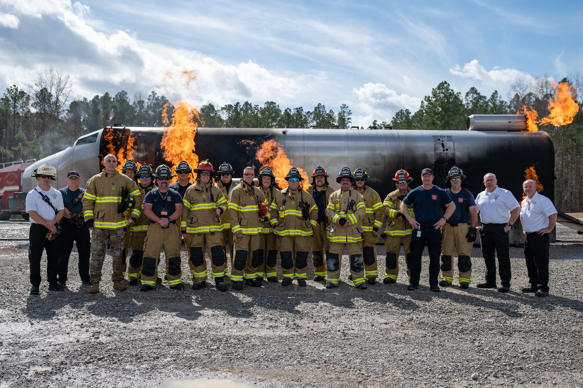 Arnold Engineering Development Complex leadership and some of the Arnold Air Force Base Fire and Emergency Services firefighters who participated in the recent live fire training conducted by Arnold FES pose for a photo in front of an aircraft fuselage fire simulator March 6, 2026, at Arnold AFB, Tenn. Arnold AFB is the headquarters of AEDC. The annual training is conducted by FES to maintain readiness in the event of an emergency and to meet National Fire Protection Association and Air Force requirements. Arnold AFB is the headquarters of AEDC. (U.S. Air Force photo by Keith Thornburgh)