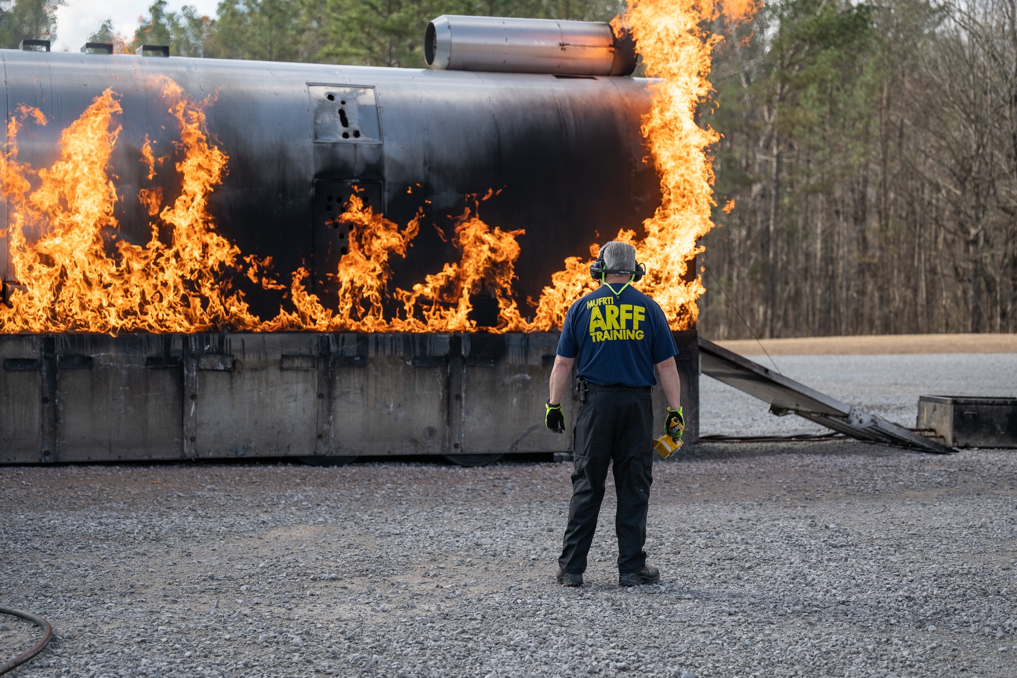 Greg Smith with the University of Missouri Fire and Rescue Training Institute, or MUFRTI, looks on as a simulated aircraft fuselage is ignited for live fire training at Arnold Air Force Base, Tenn., March 6, 2026. Arnold AFB Fire and Emergency Services firefighters participated in the annual training to maintain readiness in the event of an emergency and to meet National Fire Protection Association and Air Force requirements. The mock fuselage, used to simulate aircraft fires, was once again brought to Arnold from MUFRTI. (U.S. Air Force photo by Keith Thornburgh)