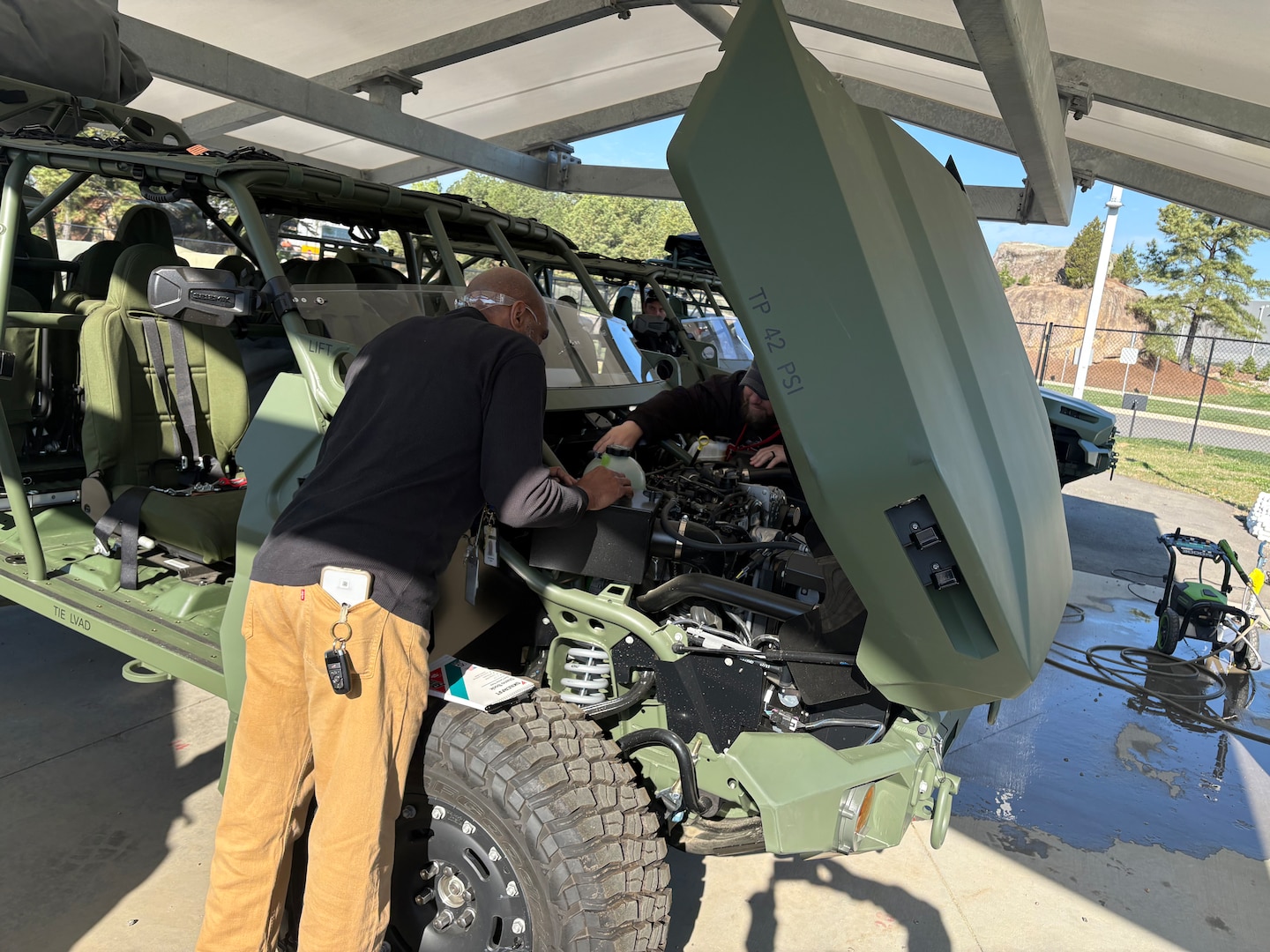 Two men look at a green military vehicle