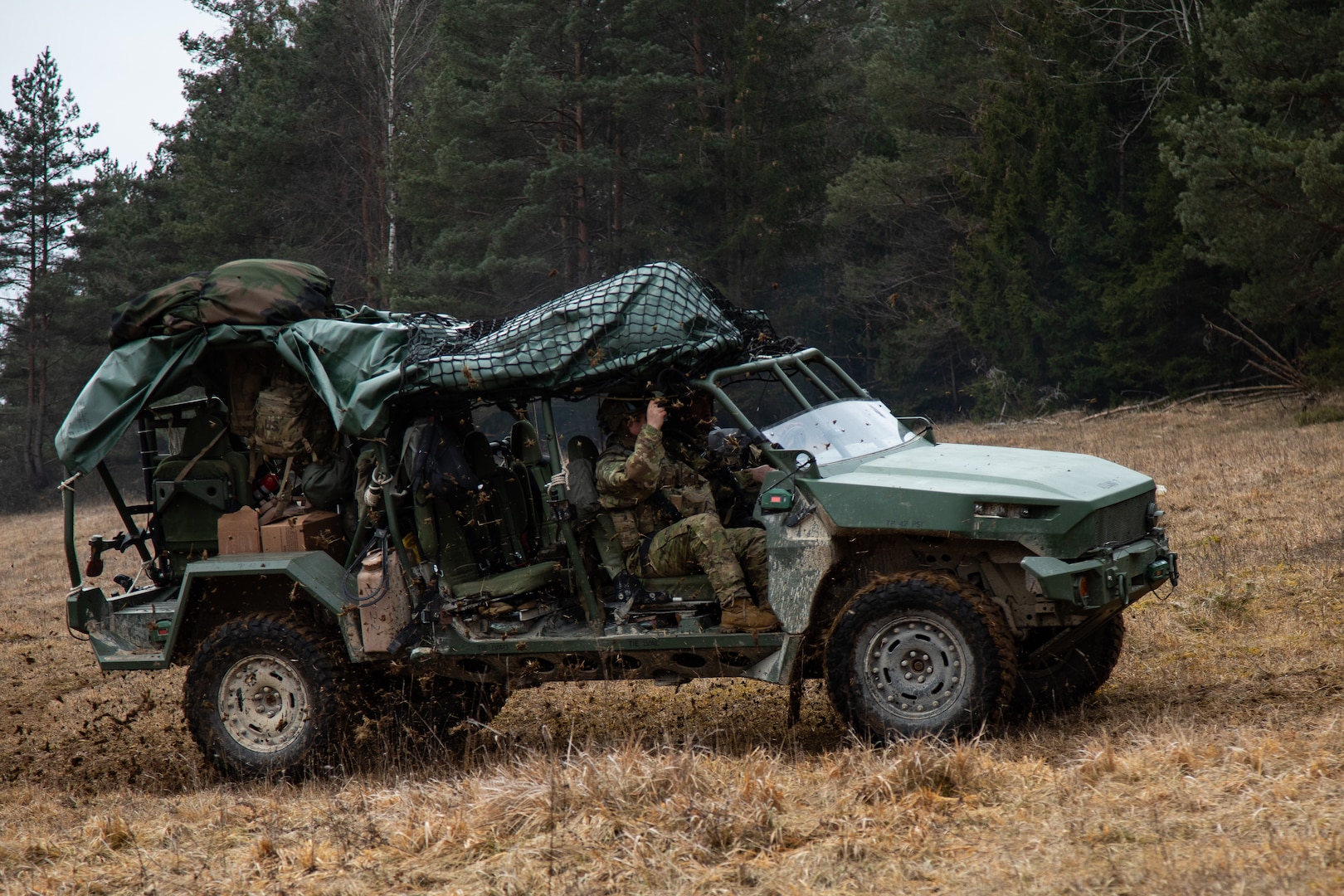 A group of soldiers drive a green military vehicle