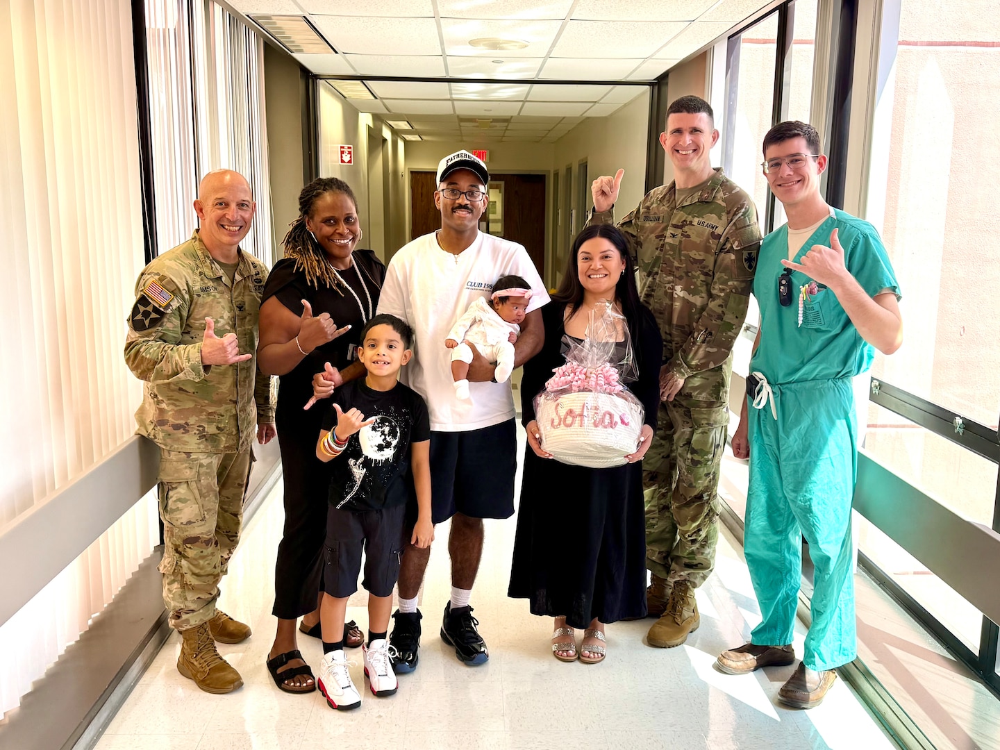 U.S. Army Staff Sgt. Yeni A. Conquest, center right, a mortuary affairs non-commissioned officer with 8th Theater Sustainment Command (8th TSC), and U.S. Navy Petty Officer 2nd Class Blake A. Conquest, center left, an aviation electronics technician with Marine Aviation Logistics Squadron 24, pose for a group photo with U.S. Army Col. William F. Bimson (left), Tripler Army Medical Center (TAMC) director, Melissa Jones, second from left, TAMC midwife, Col. John P. Sullivan, second from right, director, G-3, 8th TSC, and Capt. Remington Schmidt, right, an obstetrics and gynecology resident, during a celebration event at TAMC on April 3. The event recognized the Conquests as parents of the eighth baby born to the 8th TSC this year. (Courtesy photo by Maj. Grant Gainsley)