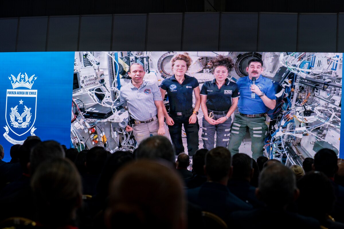 Attendees watch a video message from astronauts aboard the International Space Station during the opening ceremony of the Feria Internacional del Aire y del Espacio (FIDAE) 2026 in Santiago, Chile, April 7, 2026. The message sent as a greeting from 400 km above earth highlighted global cooperation in space and reinforced the importance of international partnerships during Latin America’s largest aerospace and defense exhibition. (U.S. Air Force photo by Andrea Jenkins)