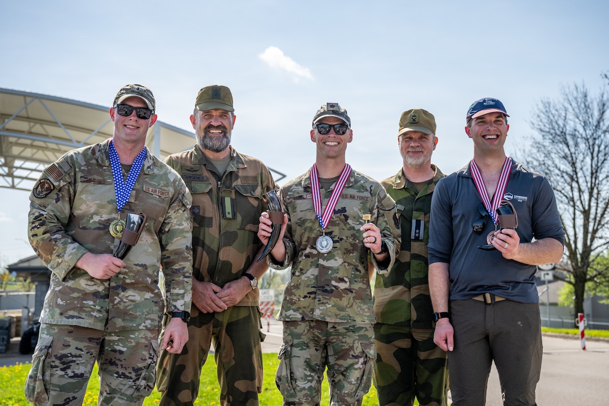 Five men pose for a group photo. The three in the front wearing gold, silver, and bronze medals