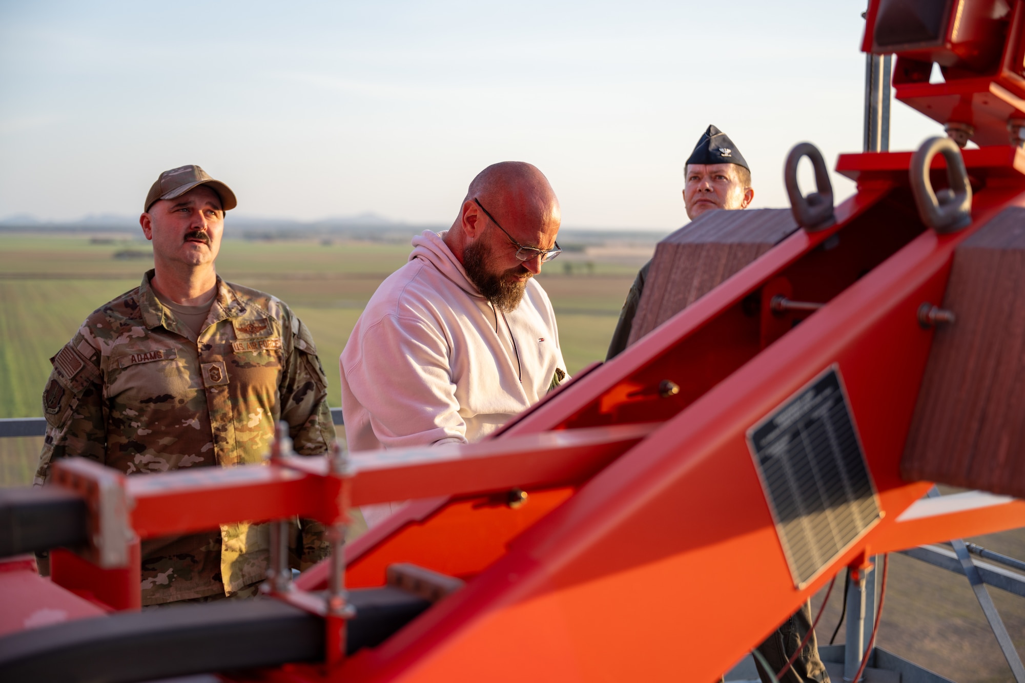 U.S. Air Force Col. Richard Kind, 97th Air Mobility Wing commander, right, and Chief Master Sgt. Jonny Adams, 97th Air Mobility Wing command chief, left, listen as Josh Barclay, 97th Operations Support Squadron radar airfield and weather systems lead technician, center, explains the digital airport surveillance radar at Altus Air Force Base, Oklahoma, March 30, 2026. The radar provided aircraft surveillance and weather information to support local air traffic operations. (U.S. Air Force photo by Airman 1st Class Nathan Langston)