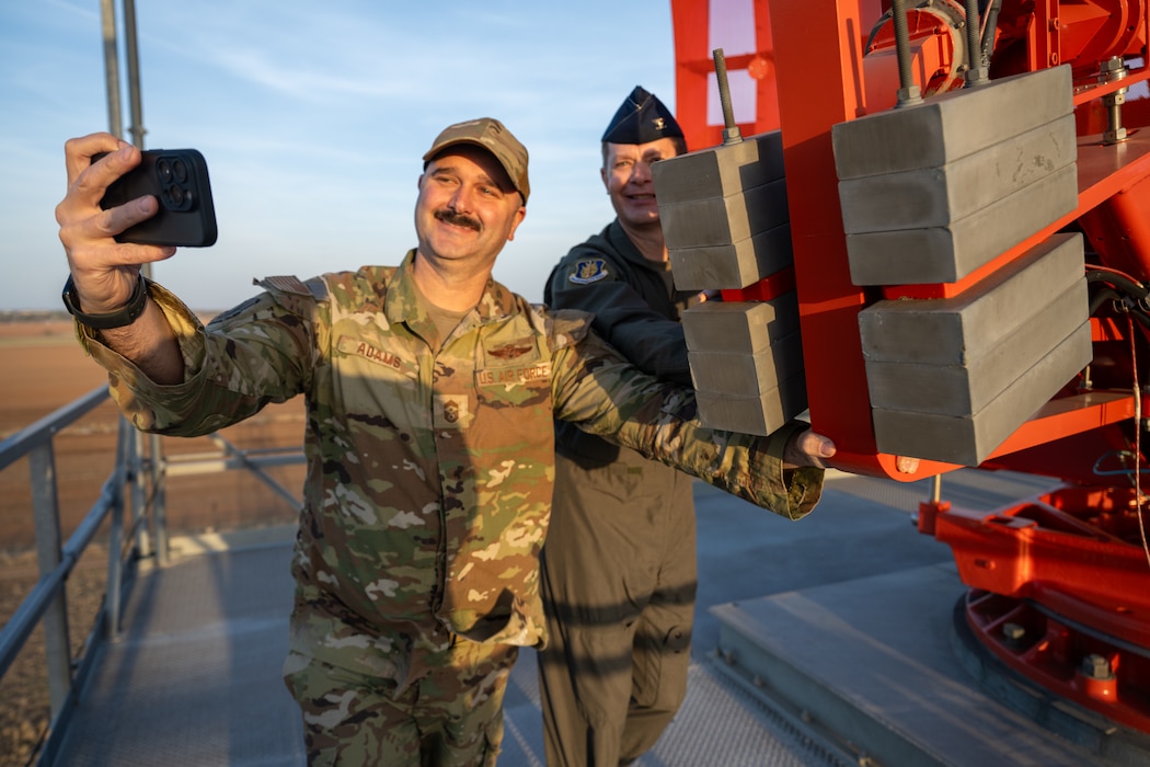 U.S. Air Force Col. Richard Kind, 97th Air Mobility Wing commander, right, and Chief Master Sgt. Jonny Adams, 97th Air Mobility Wing command chief, left, push the rotating assembly of a digital airport surveillance radar during a demonstration at Altus Air Force Base, Oklahoma, March 30, 2026. The radar was balanced with counterweights to maintain smooth rotation at high speeds. (U.S. Air Force photo by Airman 1st Class Nathan Langston)