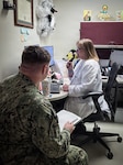 Dr. Rebecca Carlin, right, charts patient notes aboard Navy Medicine Readiness and Training Command Cherry Point on Thursday, April 2, 2026.  Carlin is a medical provider in the facility’s Patient Centered Medical Home and cares for the spouses and children of Sailors and Marines stationed at the base, helping them remain focused on training and preparing for deployment.
