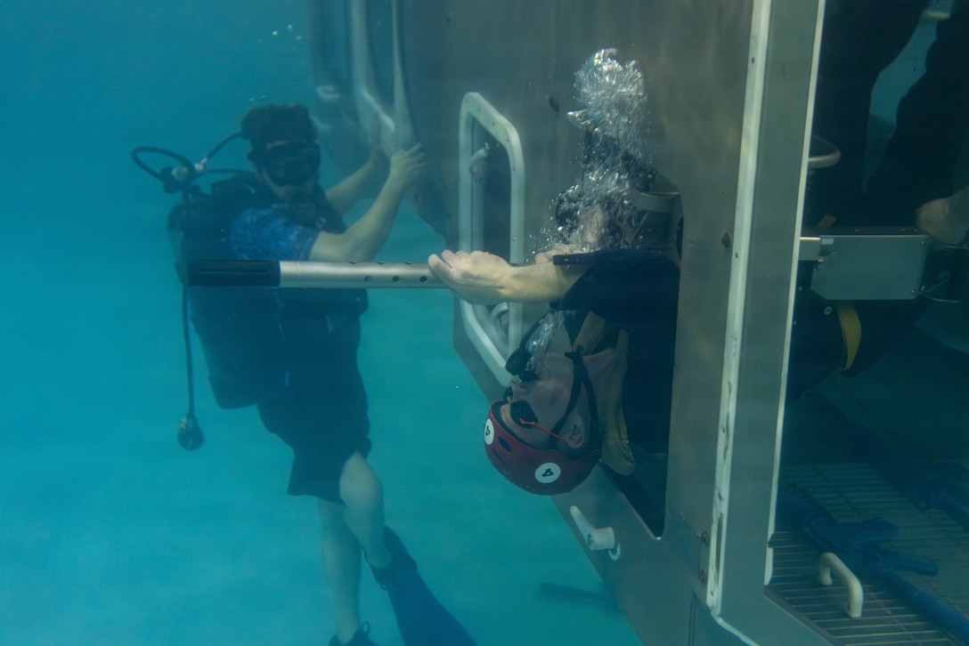 U.S. Marine Corps Capt. William Reckley, a communication strategy and operations officer with II Marine Expeditionary Force Support Battalion, pulls himself out of a modular amphibious egress trainer (MAET) during underwater egress training at Marine Corps Base Camp Lejeune, North Carolina, March 24, 2026. UET provides Marines and Sailors with the skills and confidence to safely evacuate an aircraft submerged in water. (U.S. Marine Corps photo by Lance Cpl. Channah Chilton.)