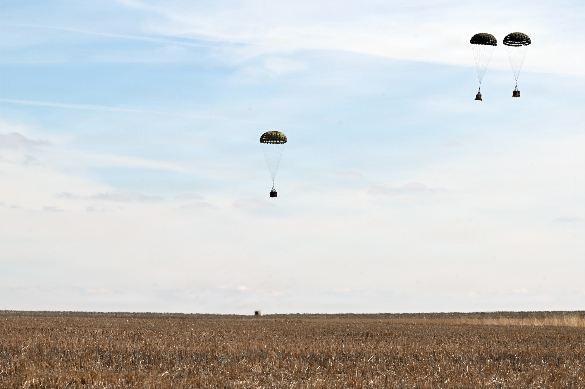 Cargo bundles approach the ground during an aerial delivery operation at the Vigilante Drop Zone near Power, Montana, April 6, 2026.
