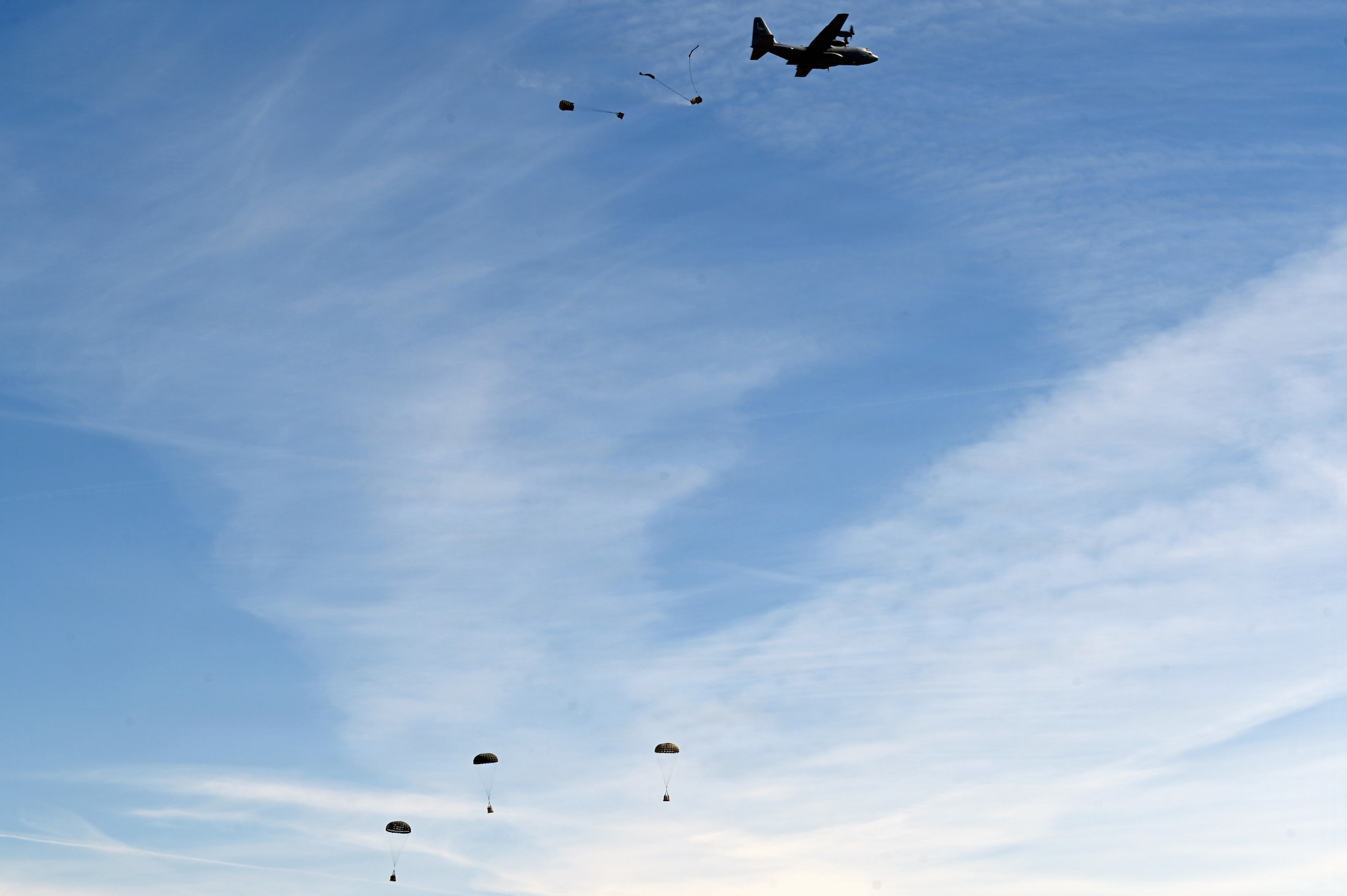 A U.S. Air Force C-130H aircraft assigned to the 120th Airlift Wing releases cargo bundles during an aerial delivery mission over the Vigilante Drop Zone near Power, Montana, April 6, 2026.
