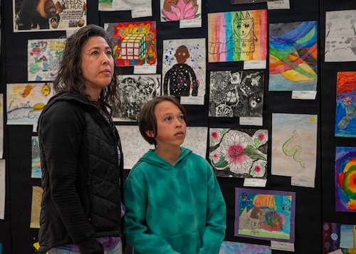 Lori Dudley, Month of Military Child picnic attendee, and her son Liam Dudley, Osan Elementary School student, look at art at Osan Air Base, Republic of Korea, April 8, 2026. During the picnic, families were able to visit different booths where students showcased the artwork they created throughout the school year highlighting their growth and accomplishments. (U.S. Air Force photo by Staff Sgt. Sarah Williams)