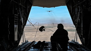 A U.S. Air Force loadmaster assigned to the 120th Airlift Wing observes cargo bundles descending over the Vigilante Drop Zone during an aerial delivery mission near Power, Montana, April 6, 2026.