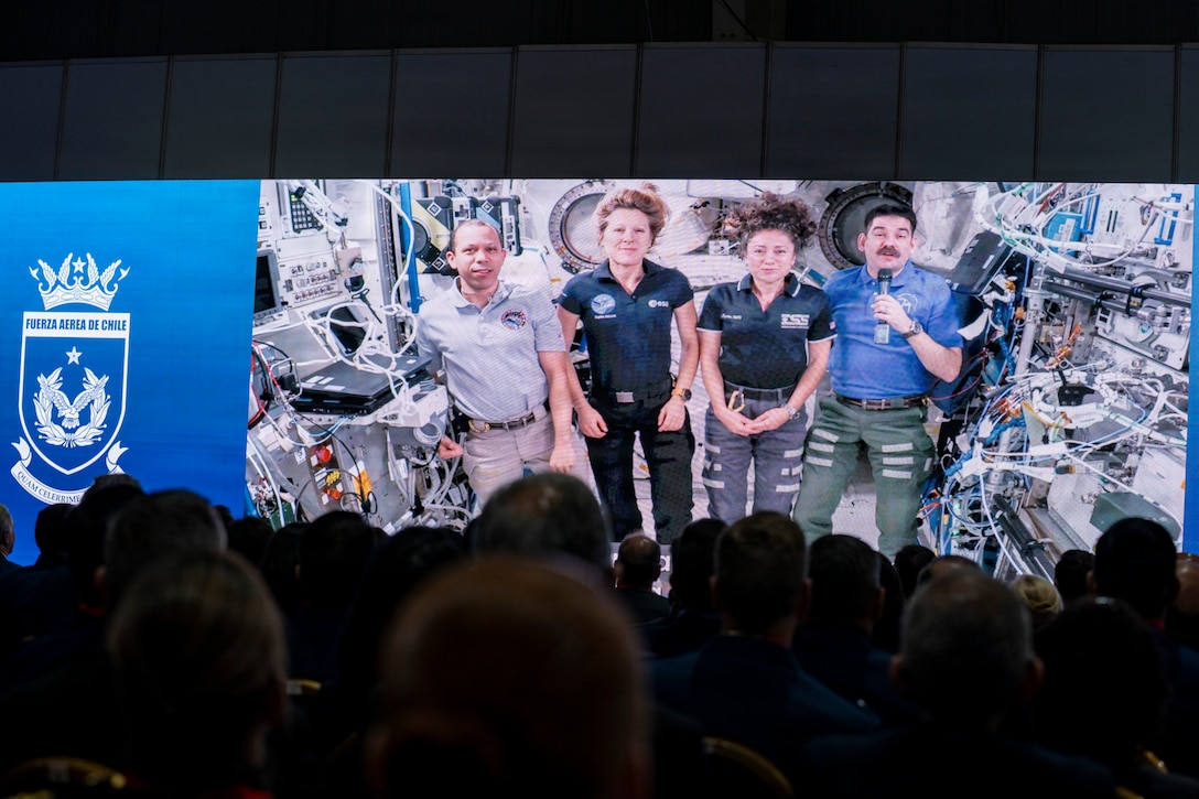 Attendees watch a video message from astronauts aboard the International Space Station during the opening ceremony of the Feria Internacional del Aire y del Espacio (FIDAE) 2026 in Santiago, Chile, April 7, 2026. The message sent as a greeting from 400 km above earth highlighted global cooperation in space and reinforced the importance of international partnerships during Latin America’s largest aerospace and defense exhibition. (U.S. Air Force photo by Andrea Jenkins)