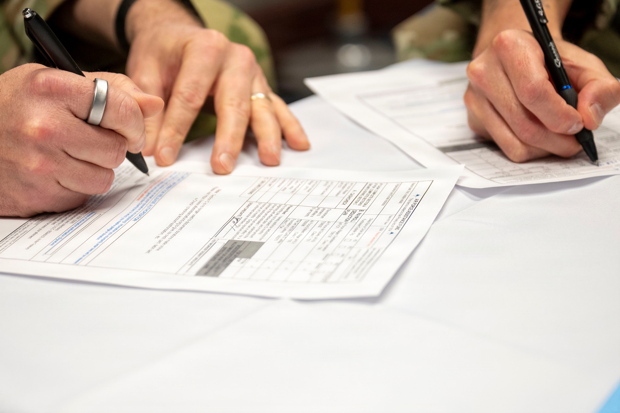 Image of two sets of hands signing documents