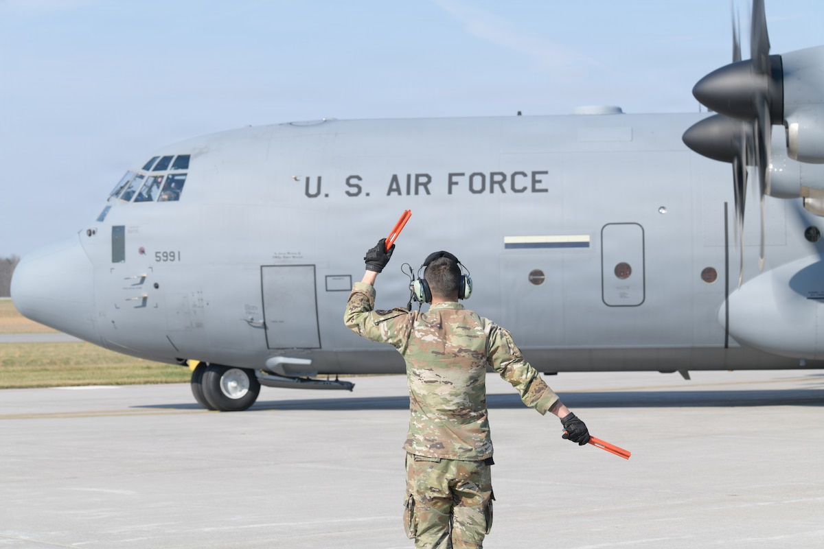 A member of the 910th Aircraft Maintenance Squadron marshals a C-130J Super Hercules for takeoff at Youngstown Air Reserve Station, Ohio, March 26, 2026. The 910th Airlift Wing maintains and operates a fleet of C-130J and C-130H aircraft to provide tactical airlift and aerial spray capabilities as it transitions to the new J models. (U.S. Air Force photo by Eric M. White)