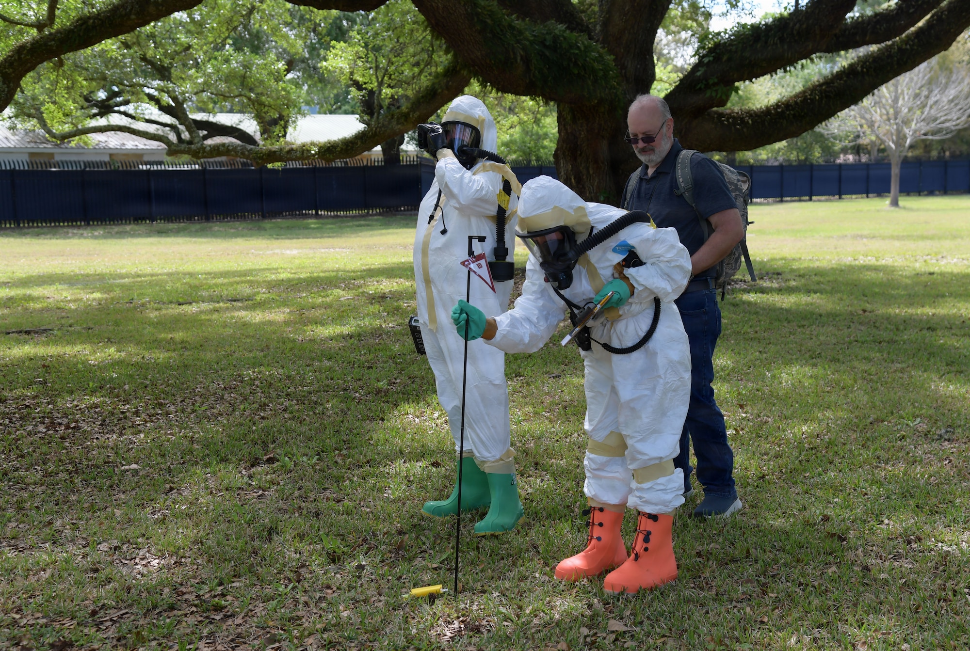 People wearing white hazmat suits stick a pole in the ground.