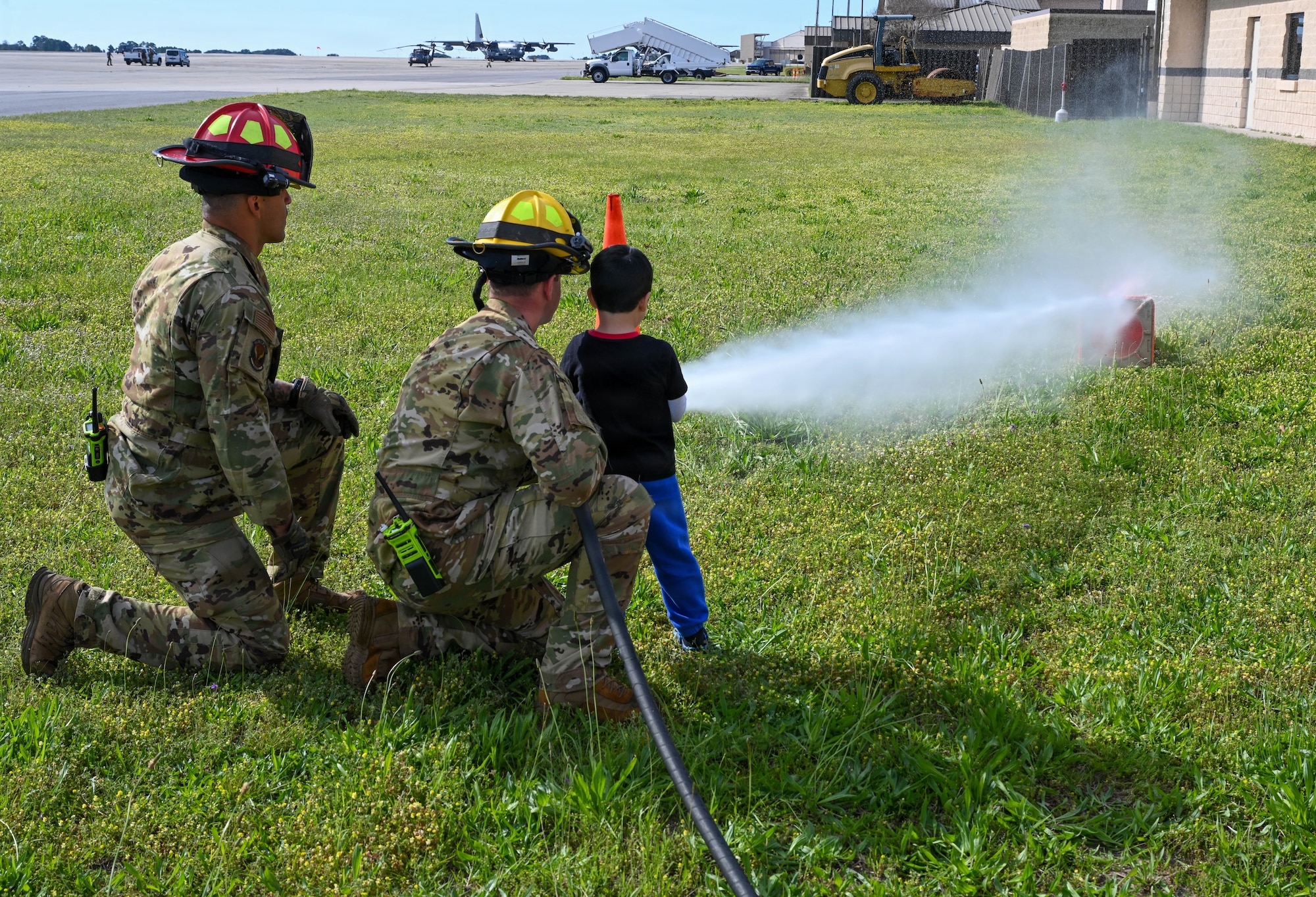 Firefighters help a child spray a hose
