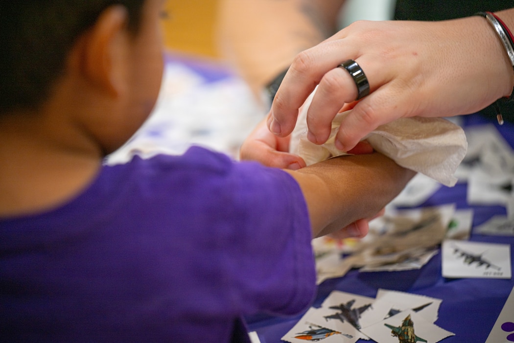 A teacher applies a temporary tattoo onto a child's are.