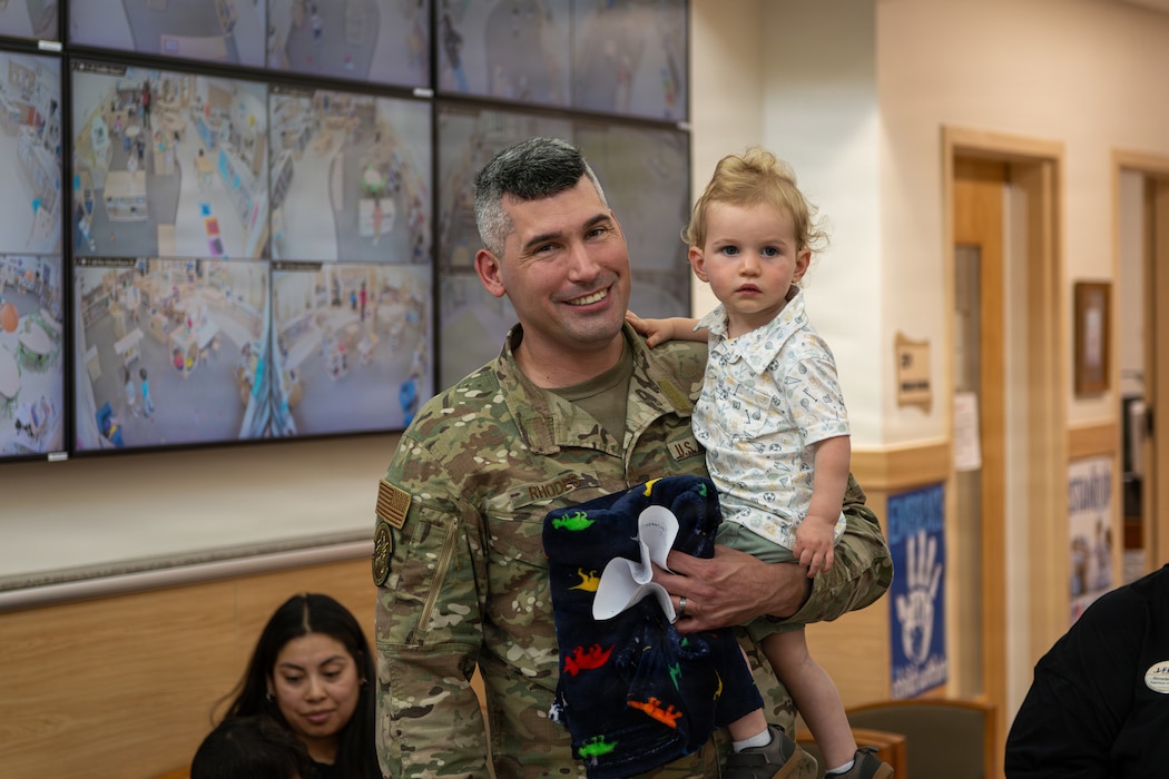 Father holds young son and poses for a photo.