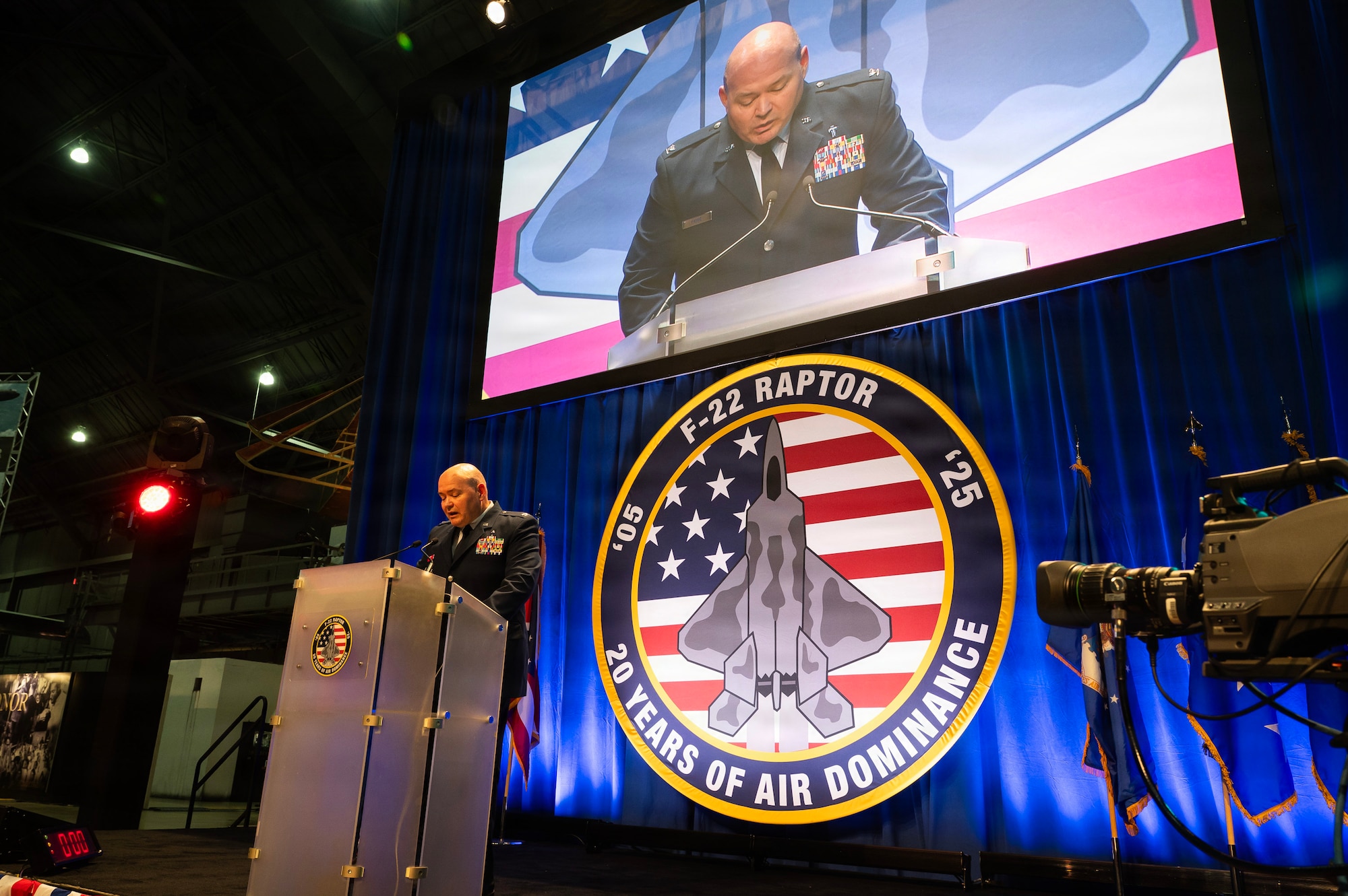 Group of people seated at round tables looking at a screen.