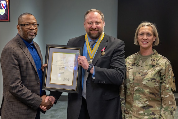 Col. Michelle M. Williams, U.S. Army Financial Management Command commander, right, and Retired Command Sgt. Maj. Gennaro Penn, U.S. Army Finance Corps Association president, left, present Ryan A. Busby, Deputy Assistant Secretary of the Army for Financial Operations and Information, with a U.S. Army Finance Corps’ Honorary Member of the Regiment award on behalf of Col. Robert Le'iato, U.S. Army Finance and Comptroller School commandant and Chief of the Finance Corps, at the Maj. Gen. Emmett J. Bean Federal Center in Indianapolis Jan. 12, 2026. The Finance Corps designated the first Honorary Member of the Regiment on July 5, 1988, to honor those who made significant professional contributions or have brought great credit to the Finance Corps through special acts or accomplishments. (U.S. Army photo by Mark R. W. Orders-Woempner)