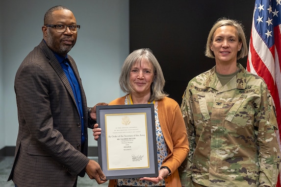Col. Michelle M. Williams, U.S. Army Financial Management Command commander, right, and Retired Command Sgt. Maj. Gennaro Penn, U.S. Army Finance Corps Association president, left, present Valerie Dillon, USAFMCOM secretary to the general staff, with a U.S. Army Finance Corps’ Honorary Member of the Regiment award on behalf of Col. Robert Le'iato, U.S. Army Finance and Comptroller School commandant and Chief of the Finance Corps, at the Maj. Gen. Emmett J. Bean Federal Center in Indianapolis Jan. 12, 2026. The Finance Corps designated the first Honorary Member of the Regiment on July 5, 1988, to honor those who made significant professional contributions or have brought great credit to the Finance Corps through special acts or accomplishments. (U.S. Army photo by Mark R. W. Orders-Woempner)
