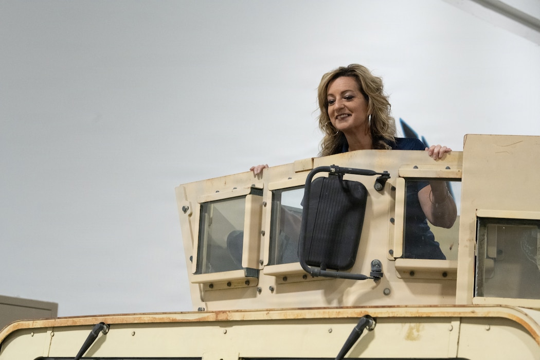 An Honorary Commander stands in a Humvee.