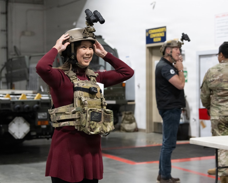 An Honorary Commander tries on a plate carrier equipped with night vision goggles.