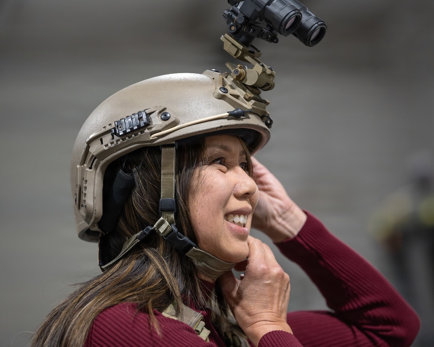 An Honorary Commander tries on a helmet equipped with night vision goggles.