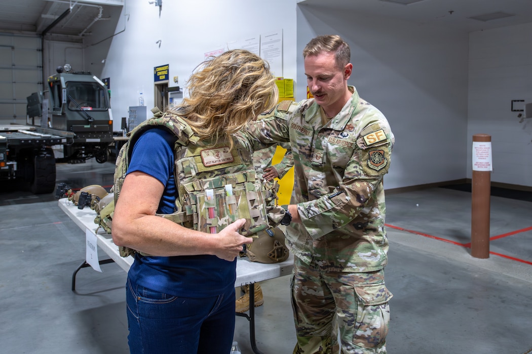 An Airman helps an Honorary Commander try on a plate carrier.