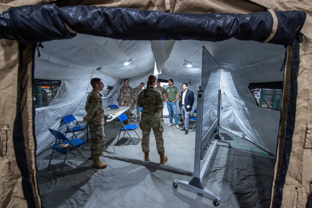 Airmen speak with Honorary Commanders inside a tent.