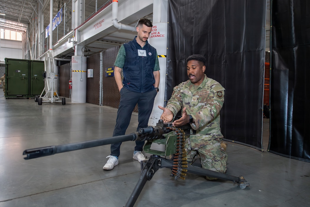 An Airman shows an Honorary Commander a machine gun.