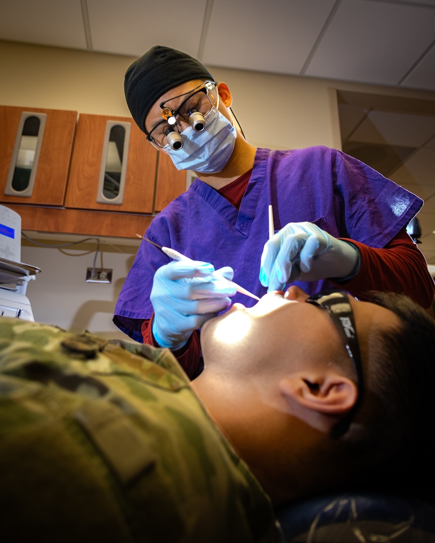 Fourth-year dental student Tim Nguyen examines a Soldier at a Fort Riley dental clinic April 7, 2026. His experience at Fort Riley provided a key insight on the difference between Army and civilian dentistry. Army dentistry removes financial barriers to care, allowing providers to focus entirely on the patient's dental health and ensuring every Soldier is medically fit for their mission.