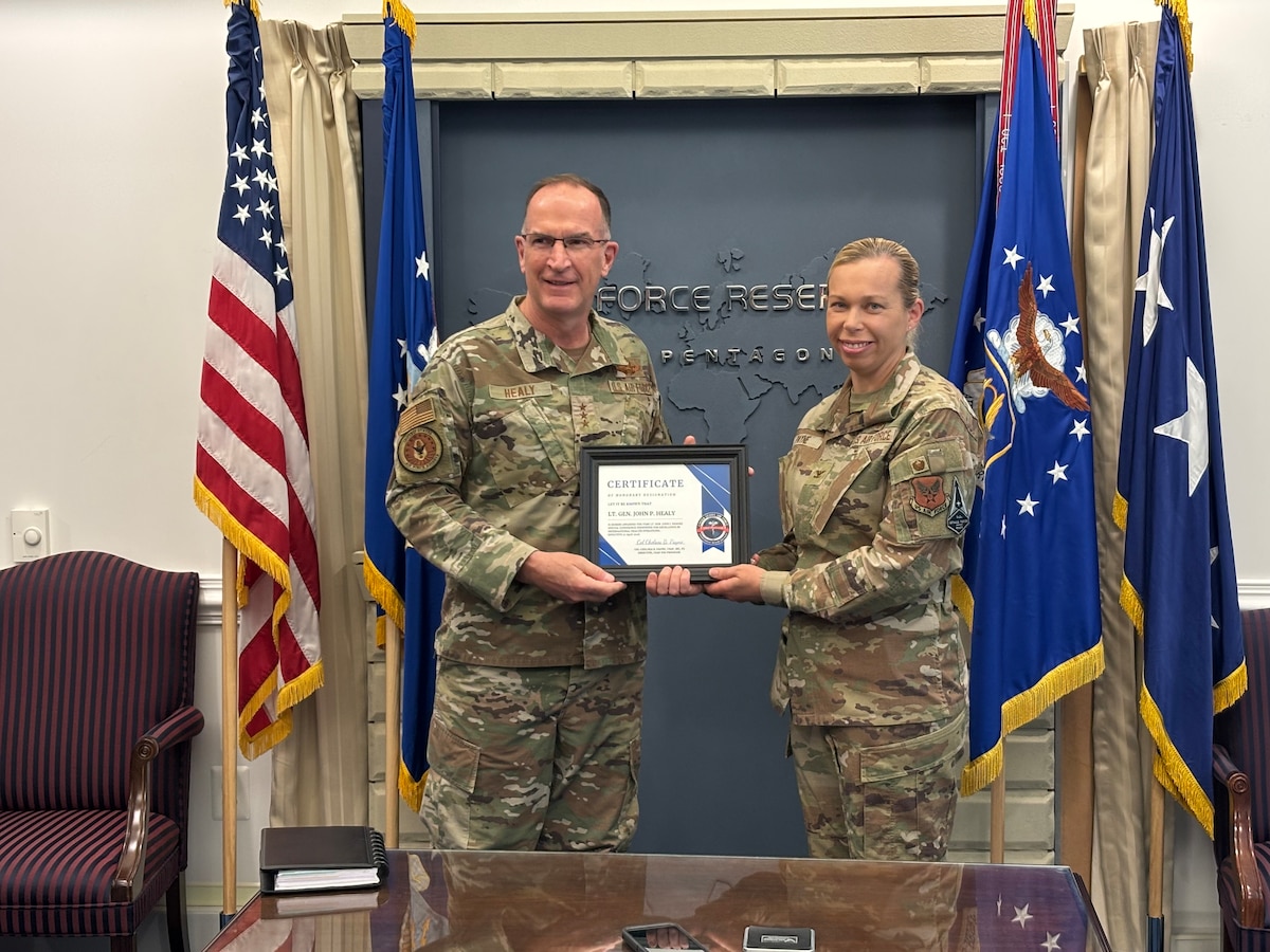 Lt. Gen. John P. Healy holds an award with another service member