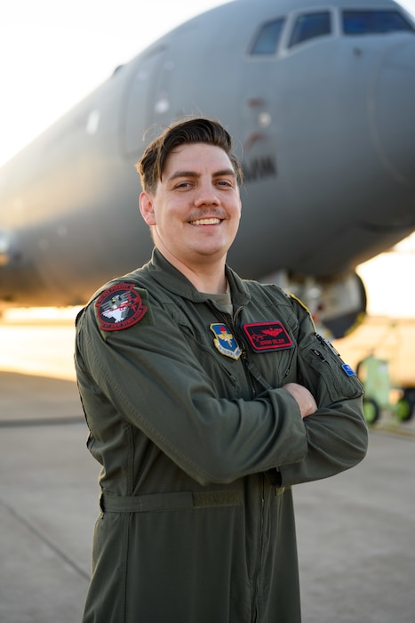 Then, U.S. Air Force Capt. Jeremy Delzer, 56th Air Refueling Squadron KC-46 Pegasus aircraft instructor pilot and demo team lead, poses for a photo in front of a KC-46 at Altus Air Force Base, Oklahoma, March 13, 2025. As a member of the KC-46 demonstration team, Delzer helps educate the public on the aircraft's advanced refueling and cargo transport capabilities during air show performances. (U.S. Air Force photo by Airman 1st Class Jonah Bliss)