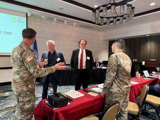 2 men in uniforms talk to 2 men in suits