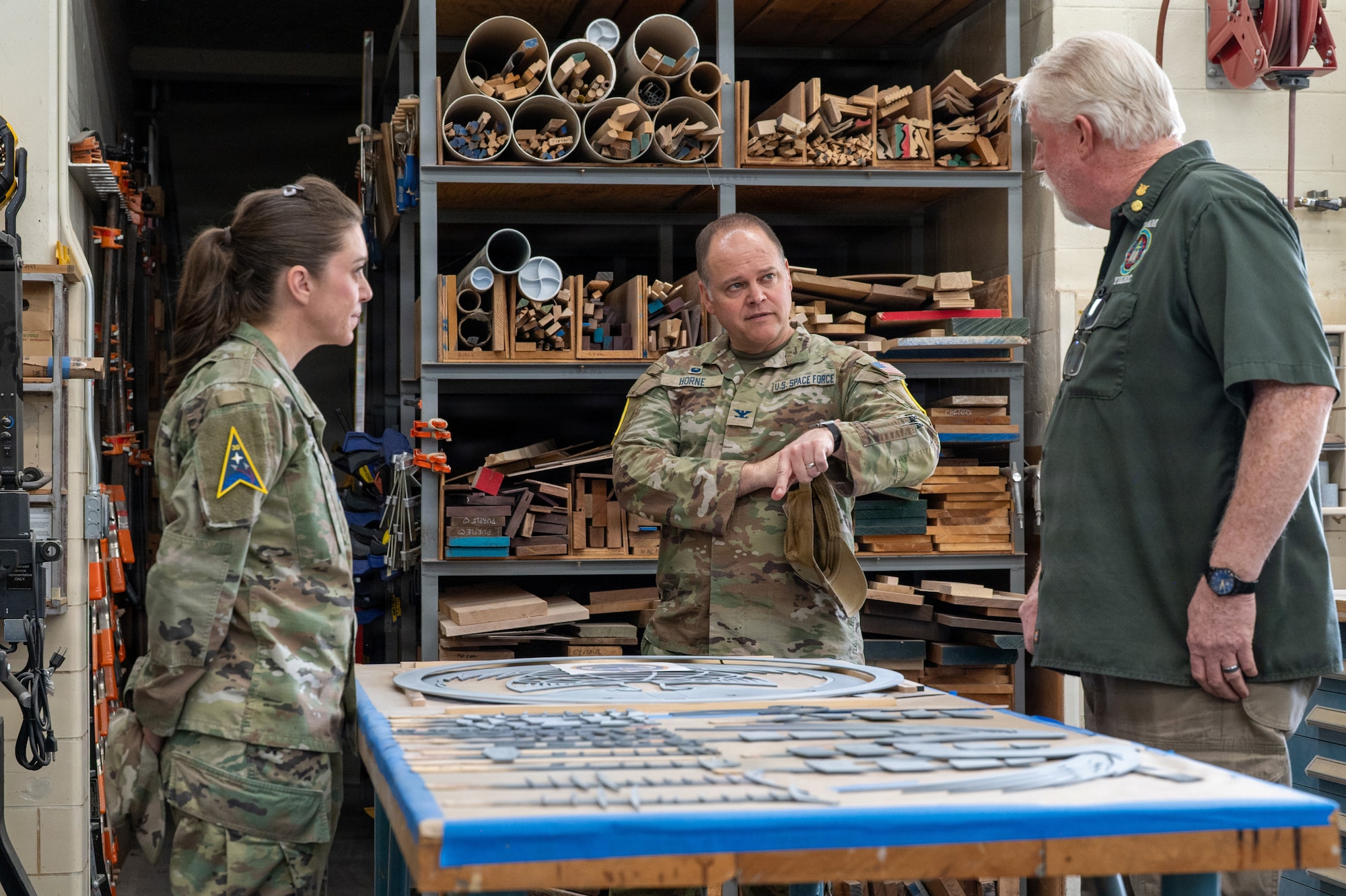 U.S. Space Force Col. James T. Horne III, center, Space Launch Delta 30 commander, stands and inquires about wood carving procedures.