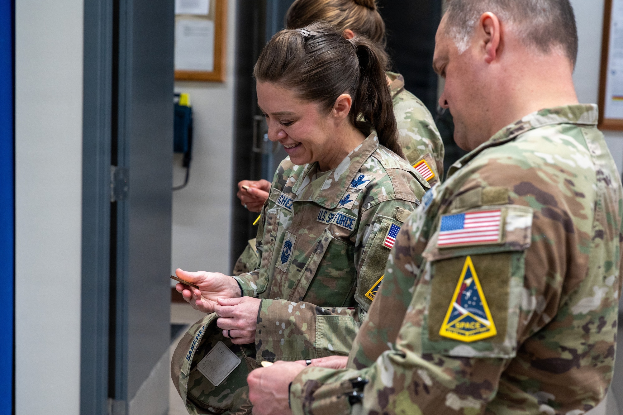 Two Space Launch Delta 30 leadership members stand and receive wooden coins, they hold them in their hands.