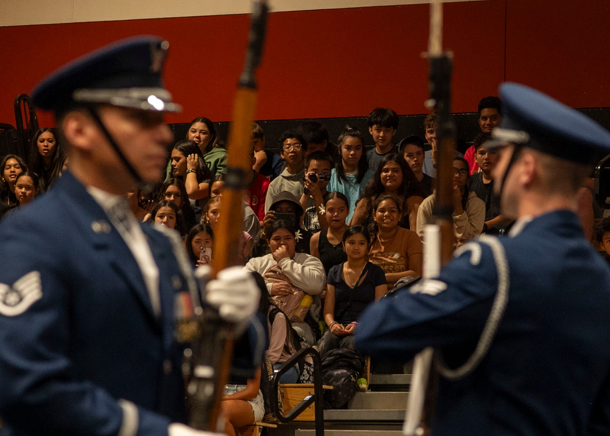 Students watch from gymnasium bleachers as the drill team performs.